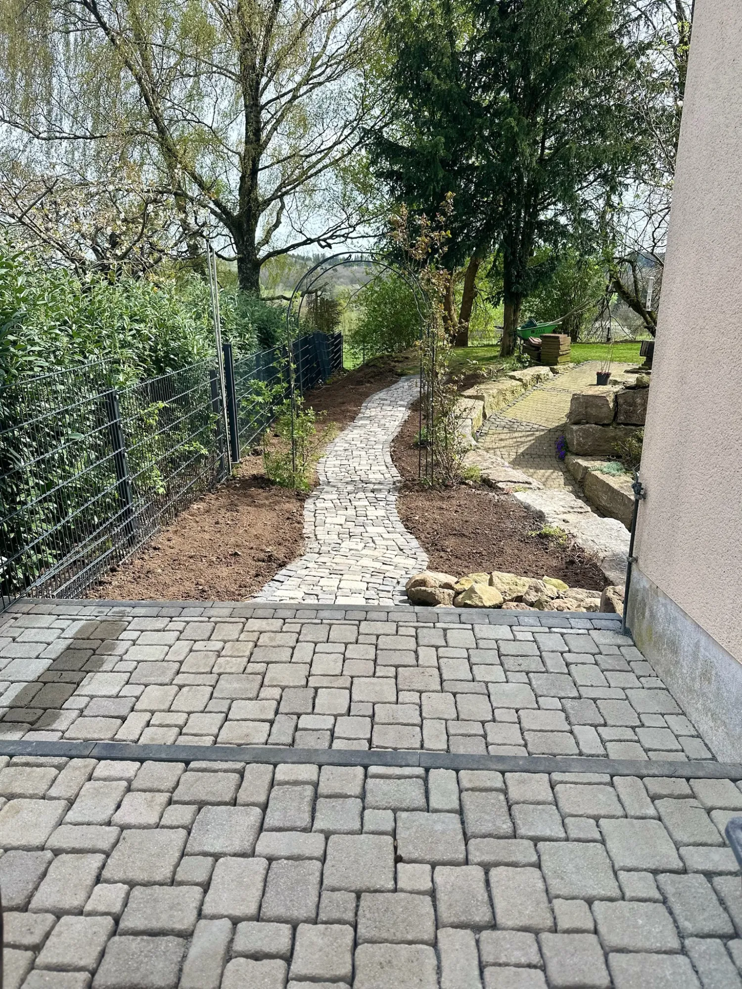 Neugestalteter Gartenweg mit Pflasterung und Natursteinen an leichtem Hang